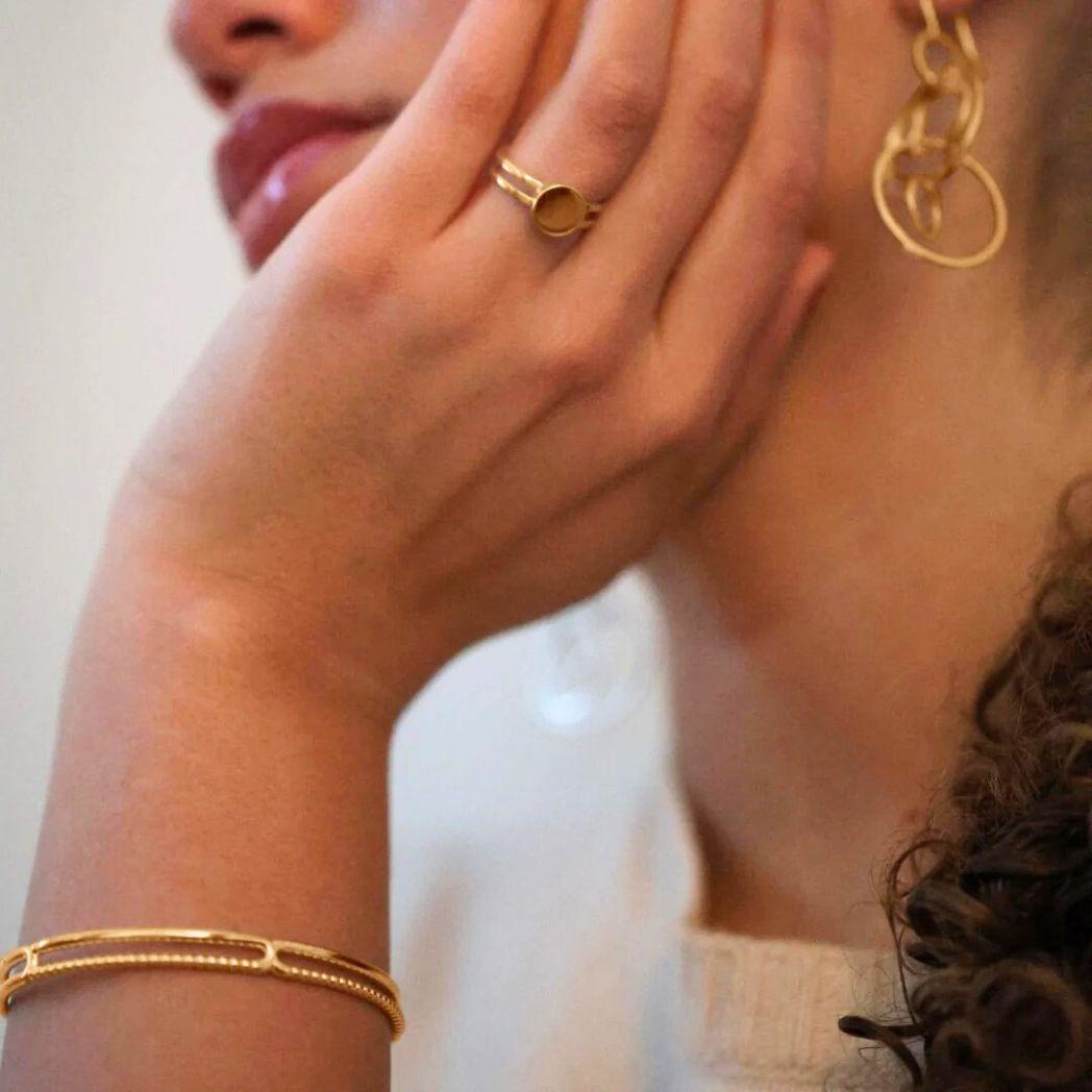 Ring, armband och örhänge i guld på modell