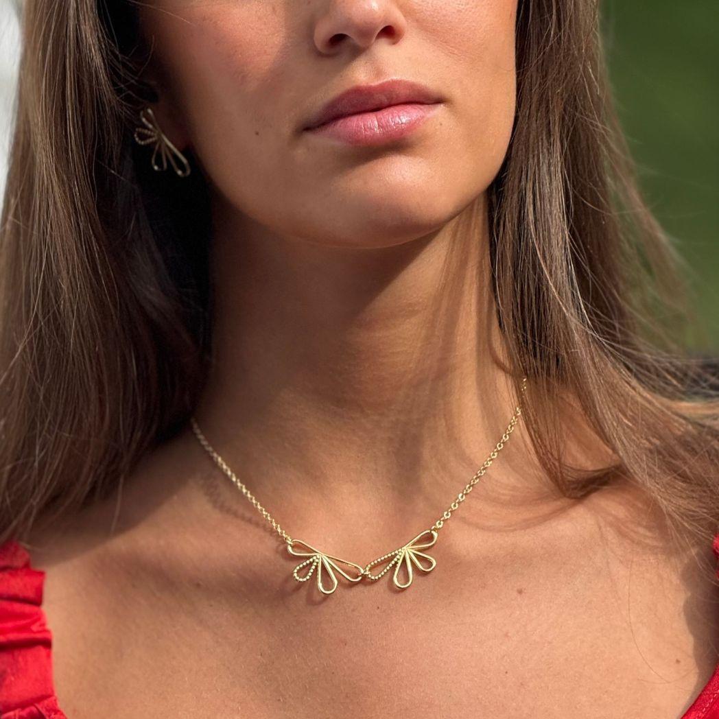 Närbild på blomformat halsband i guld 